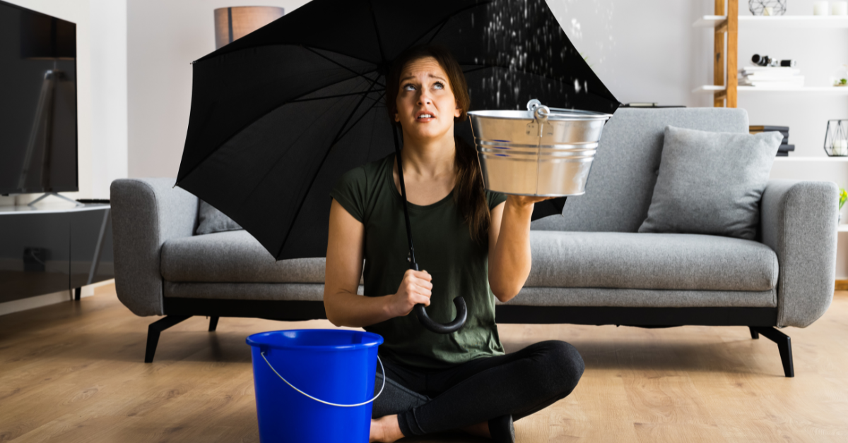 women struggling to catch all the water from a burst pipe